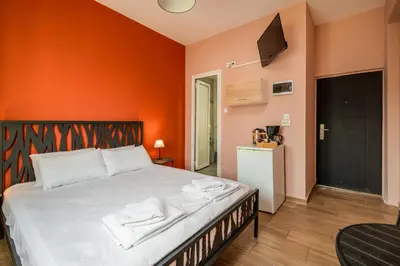 a bedroom with a bed with an orange wall at The Historical Center Studios in Athens