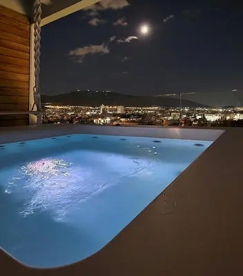 a swimming pool at night with a view of a city at One 360 Skyline Athens Penthouses in Athens