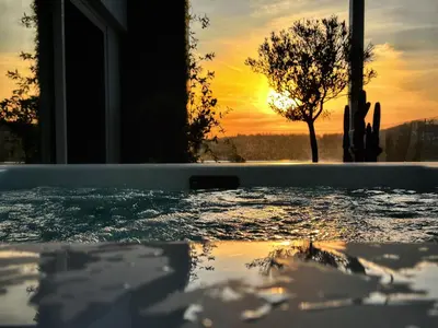 a hot tub with the sunset in the background at One 360 Skyline Athens Penthouses in Athens