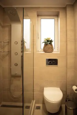 a bathroom with a shower and a toilet and a window at Traditional Thiseio Home in Athens