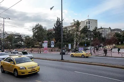 a yellow car is driving down a city street at Best neighbourhood apartment in Athens near metro station & hospitals in Athens