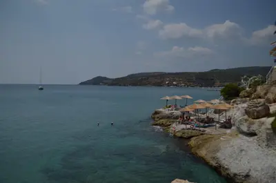 a beach with umbrellas and people in the water at Panorama Hotel in Agia Marina Aegina
