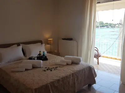 a bedroom with a bed with a view of the water at Kalos Gialos Sunrise Apartment in Porto Rafti