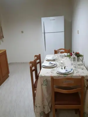 a dining room table with plates and glasses and a refrigerator at Kalos Gialos Sunrise Apartment in Porto Rafti