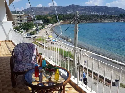 a balcony with a table and chairs and a view of the beach at Kalos Gialos Sunrise Apartment in Porto Rafti