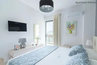 a white bedroom with a bed and a window at Apollo & Artemis by Heloni Apartments in Athens