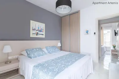 a white bed with blue pillows in a bedroom at Apollo & Artemis by Heloni Apartments in Athens