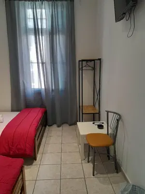 a bedroom with a bed and a table and a window at Ikaros in Piraeus