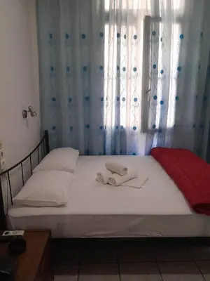 a bedroom with a bed with white sheets and a window at Ikaros in Piraeus
