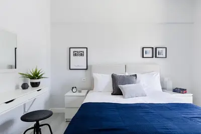 a white bedroom with a blue bed and a stool at Minimal 2BD Apartment with Lycabettus view by UPSTREET in Athens