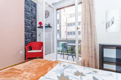 a bedroom with a bed and a window with a red chair at Petaluda House 3 in Athens