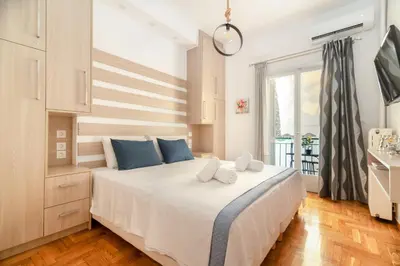 a bedroom with a large white bed with blue pillows at Hermes by Heloni Apartments in Athens
