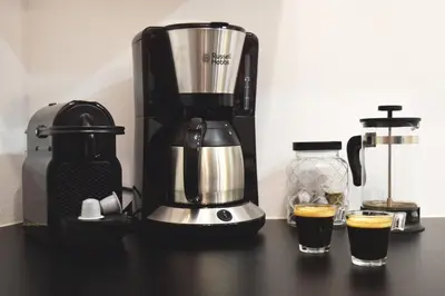 a coffee maker sitting on a counter with two glasses of coffee at Hermes by Heloni Apartments in Athens