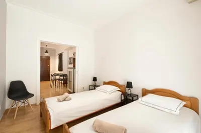 two beds in a room with white walls and wooden floors at Scent Of Freedom Apartment Renovated in Athens