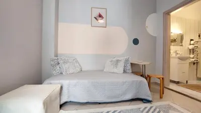 a white bedroom with a bed and a table at cozy minimal apartment in Piraeus