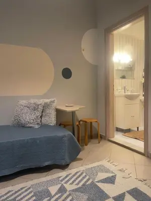 a bedroom with a bed and a table and a bathroom at cozy minimal apartment in Piraeus