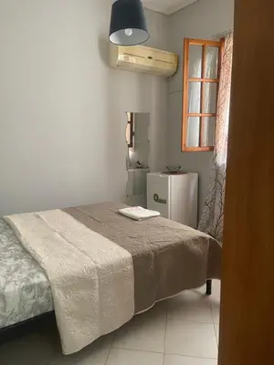 a bedroom with a bed and a small refrigerator at cozy minimal apartment in Piraeus