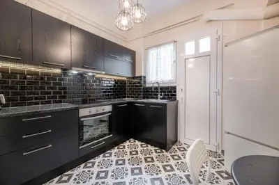 a kitchen with black cabinets and a black and white tile floor at Athens Parrot in Athens