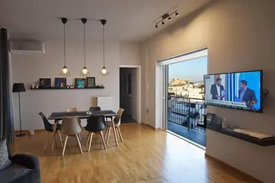 a living room with a table and a tv on a wall at Acropolis View Penthouse N in Athens
