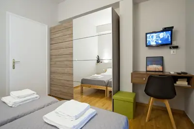 a room with two beds and a desk and a television at Acropolis View Penthouse N in Athens