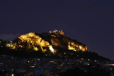 a mountain with a castle on top of it at night at Astonishing view in Athens