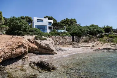 a house on a hill next to the water at The Margi Villa in Athens
