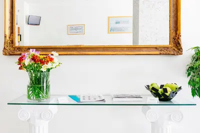 a mirror and a vase of flowers on a glass table at Phaedra Hotel in Athens