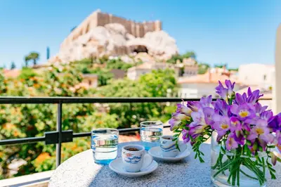 a table with a vase of flowers and glasses of water at Phaedra Hotel in Athens