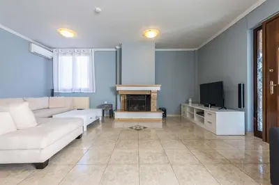 a living room with a white couch and a tv at Athens Countryside resort with pool in Pallíni