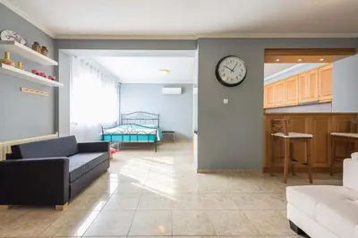 a living room with a couch and a clock on the wall at Athens Countryside resort with pool in Pallíni