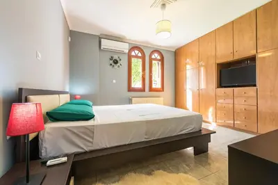 a bedroom with a large bed and a television at Athens Countryside resort with pool in Pallíni