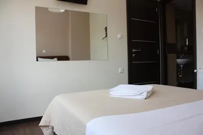 a white bed in a room with a mirror at Pella Inn Hostel in Athens