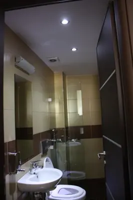 a bathroom with a sink and a toilet and a mirror at Pella Inn Hostel in Athens