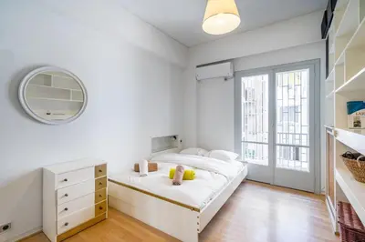 a white bedroom with a bed and a mirror at Charming and renovated flat in the heart of Athens in Athens