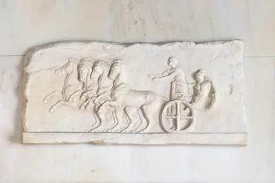 a relief of a man riding a horse on a wheel at Marble House in Athens