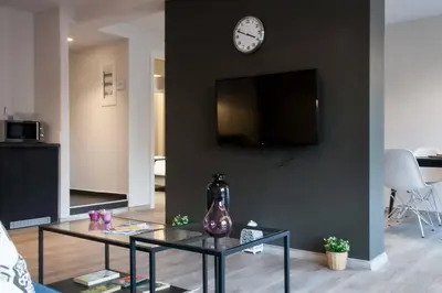 a living room with a table and a clock on a wall at TONI'S 2BD Gem House near Plaka and Syntagma in Athens