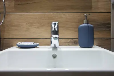 a bathroom sink with a soap dispenser and a blue bottle at TONI'S 2BD Home in Centre, 15 sec to Metro in Athens