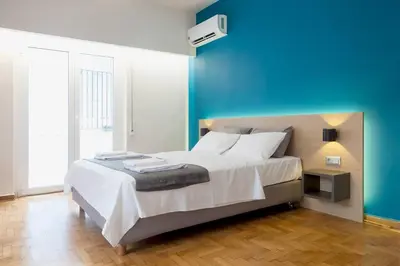 a bedroom with a large bed with a blue wall at TONI'S 2BD Home in Centre, 15 sec to Metro in Athens