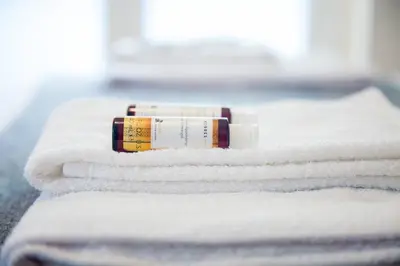 a stack of white towels with a bottle on top at TONI'S 2BD Home in Centre, 15 sec to Metro in Athens