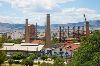 a factory with three tall smoke stacks in a city at TONI'S Charming Apartment 2BD, close Thisseo Metro in Athens