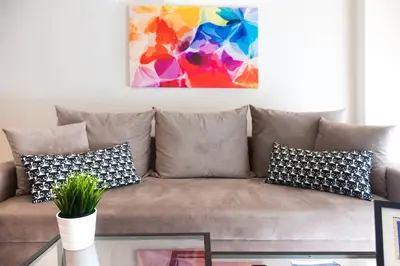 a living room with a couch with pillows and a painting at TONI'S Classy Home in Kolonaki, local's Gem in Athens