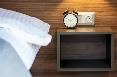 a alarm clock sitting on a table next to a bed at TONI'S Comfy 3BD home with patio, close to Metro in Athens