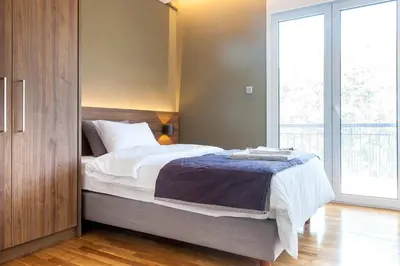 a bedroom with a bed and a large window at TONI'S Comfy 3BD home with patio, close to Metro in Athens