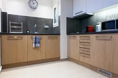 a kitchen with wooden cabinets and a clock on the wall at TONI'S Comfy home near Acropolis with Small Garden in Athens