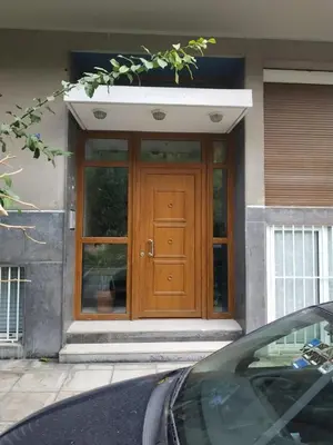 a wooden door of a house with a car in front at TONI'S Comfy home near Acropolis with Small Garden in Athens