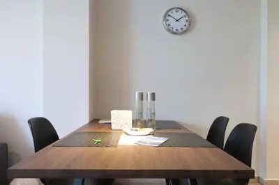 a dining room table with chairs and a clock on the wall at TONI'S Home for couples or business Travellers 1BD in Athens