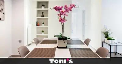 a dining room with a table with a vase of flowers at TONI'S Spacious Apartment next to Acropolis Museum in Athens