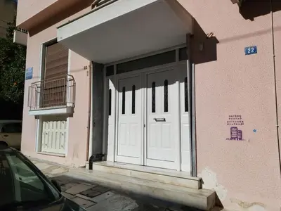 a white door on a pink building with a balcony at TONI'S Local retreat for Magicians in Koukaki in Athens