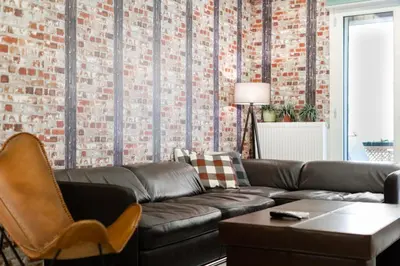 a living room with a leather couch and a brick wall at Near Acropolis brand new 1 min from metro in Athens