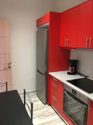 a kitchen with red cabinets and a stainless steel refrigerator at Acropolis brand new 1min from metro! in Athens